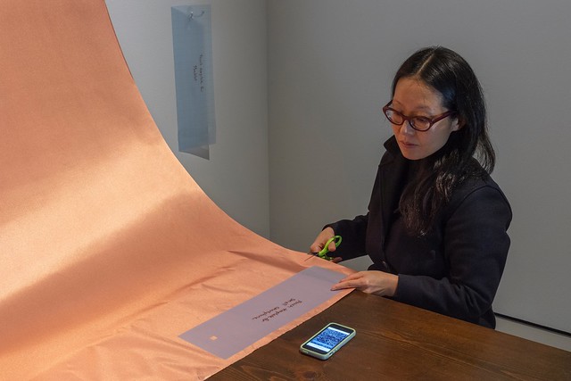 A visitor creates a signal shielding pouch for their phone in Stephanie Lynn Rogers’ AOV9 installation, Security Blanket, 2018 at Rochester Art Center. Photo by Rik Sferra.